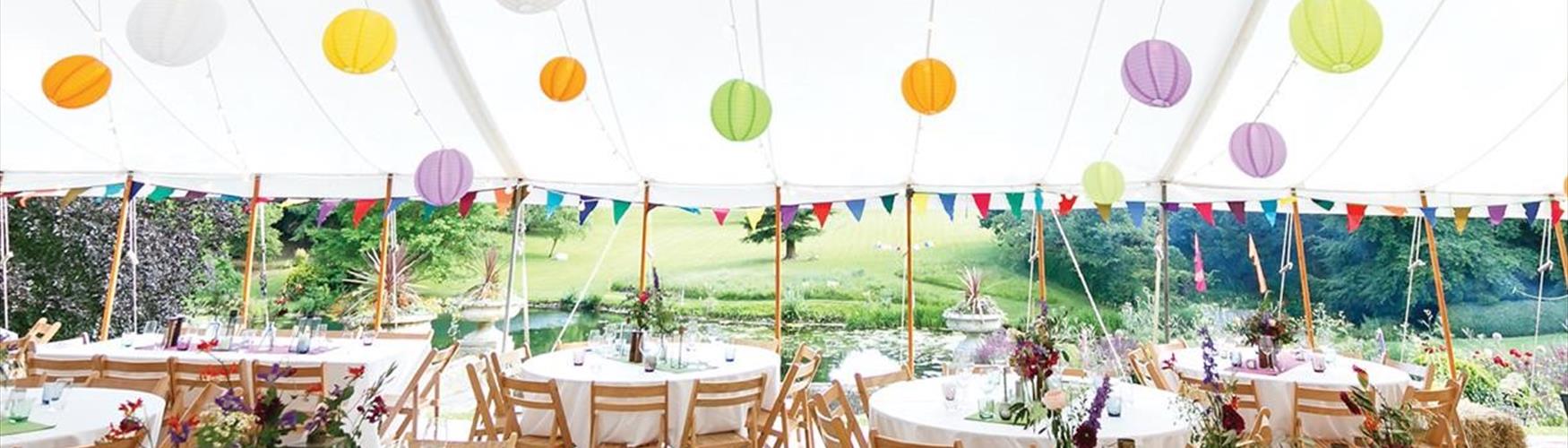 Event marquee with coloured hanging lanterns at Cowley Manor