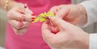 two pairs of hands close up manipulating sugar flowers and leaves