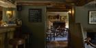 The bar area with wooden beams and floor has antique chairs by a fireplace